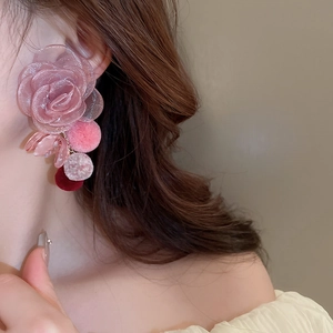 Detail of pink mesh flower earrings with soft pompom tassels on model, sweet fashion style