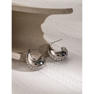 Macro shot of silver C-shaped earrings featuring channel-set sparkling white zircons