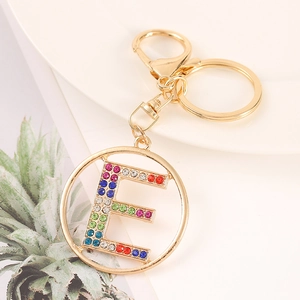 Macro shot of gold alphabet E keychain with colorful rhinestones on a white plate