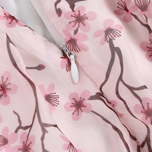 Détail d'une fermeture éclair invisible blanche sur une robe rose à imprimé fleuri cerisier