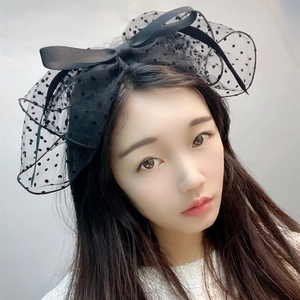 Detail of a black polka dot tulle bow headband worn by a model for elegant hair styling