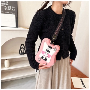 Close-up of pink guitar-shaped crossbody bag with wide shoulder strap and star studs