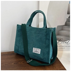 Detail of dark green corduroy tote bag with woven label on a wooden surface