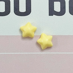 Macro detail of two bright yellow resin star charms for DIY crafts and jewelry making