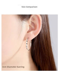 Close-up of 3cm diameter silver hoop earring with diamond-cut texture on model ear
