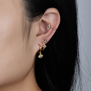Macro view of gold Evil Eye earring set with blue crystals on model's ear