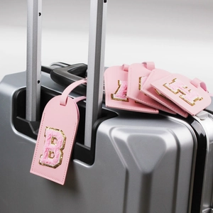 Pink PU leather luggage tag with chenille letter B patch attached to a silver suitcase