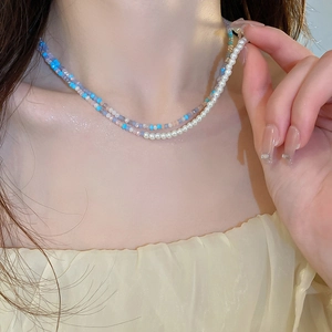 Detail of layered blue and purple bead necklace with pearls worn on neck