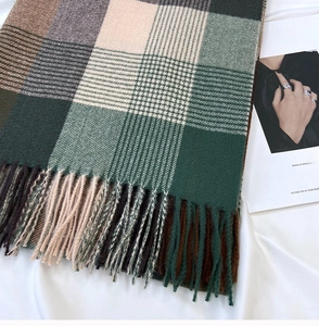 Close-up of thick plaid scarf texture with decorative fringe and luxury magazine background