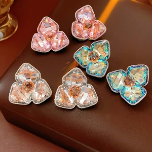 Macro detail of diamond-encrusted flower studs in pink and blue on leather