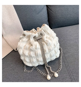 Detail of white pleated bucket bag with silver chain strap and faux pearl charm