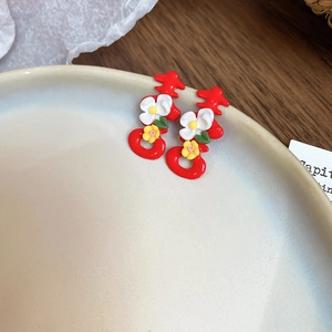 Detailed close-up of red Double Happiness studs with white flowers on ceramic tray
