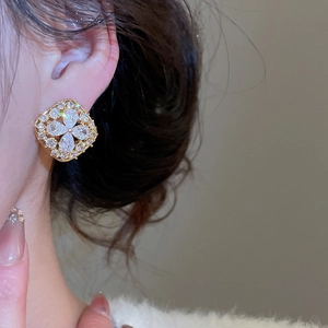 Macro detail of gold plated stud earring featuring clover shape zircon and pearl stones