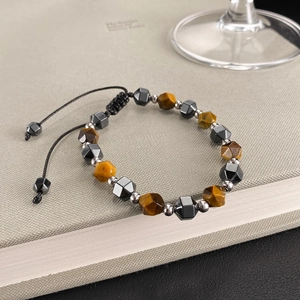 Adjustable beaded bracelet with tiger eye and black hematite on a textured book surface