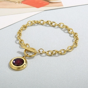 Détail du bracelet chaîne doré avec pendentif en cristal rouge foncé et fermoir OT