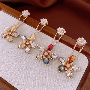 Elegant floral drop earrings with sparkling crystals and pearls on a premium wood tray