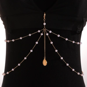 Detail of layered gold body chain with white pearls and orange teardrop pendant