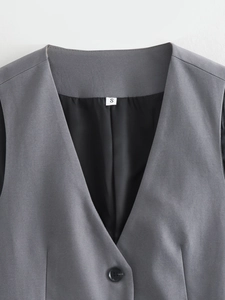 Détail du gilet gris montrant la texture tissée et l'étiquette de taille S au col