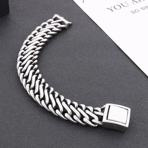 Macro shot of a heavy silver stainless steel Cuban chain bracelet with a square clasp buckle