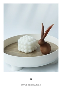 Bougie bulle blanche minimaliste et figurine lapin marron mat sur un plateau rond moderne