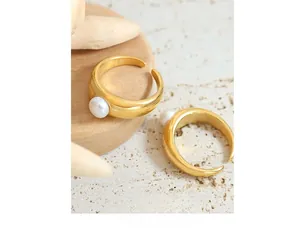 Detailed close-up of two dome-style gold plated rings featuring white freshwater pearls