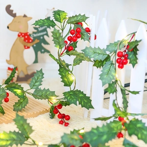 Detail of festive Christmas garland with red berries, green leaves and warm LED lights