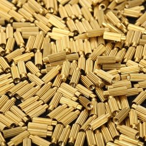 Macro shot of pile of gold brass cylindrical hardware inserts with knurled texture