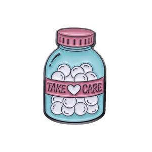 Cartoon enamel medicine bottle brooch with Take Care text and heart on light blue finish