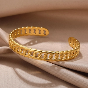 Detailed close-up of golden Cuban chain style open bangle on champagne silk background