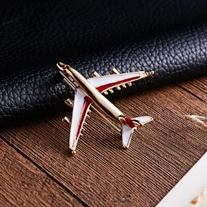 Macro shot of gold alloy airplane brooch with colorful enamel on dark leather background