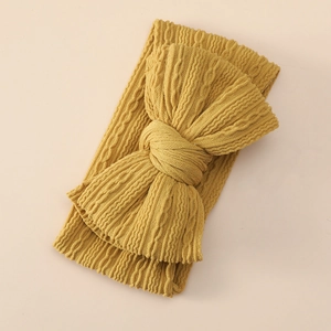 Close-up of ginger yellow knit baby headband with a soft jacquard bow texture