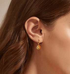 Close-up of golden Evil Eye drop earring with clear crystal on a model ear