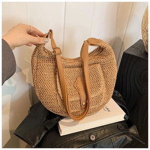 Detail of handcrafted woven straw bag with brown leather strap and shield patch detail