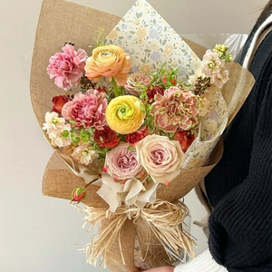 Mixed floral bouquet with pink roses and natural raffia bow in vintage paper wrap