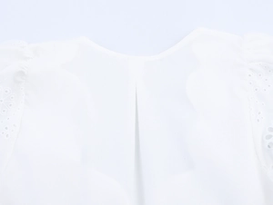 Détail de la blouse blanche en coton avec col rond, pli creux et broderie ajourée