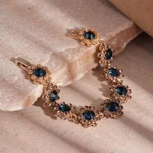 Detail of floral link necklace with blue crystal and pavé stones on stone background