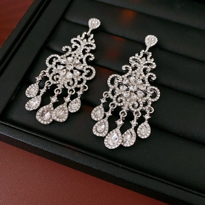 Macro view of vintage silver chandelier earrings with clear crystals on black velvet
