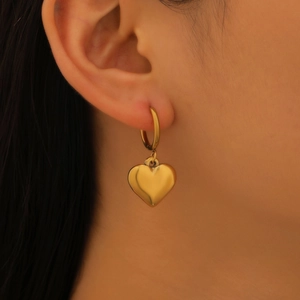 Gros plan d'une boucle d'oreille dorée avec pendentif en cœur poli pour femme