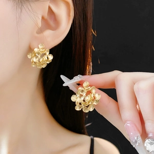 Detail of gold floral stud earrings featuring 3D metallic flower design for women