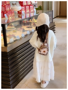 Rear view of child wearing cute cartoon brown crossbody bag in a warm bakery setting