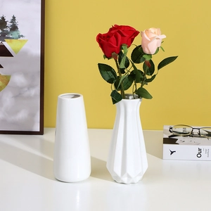 Close-up of modern white ceramic vases with roses and geometric faceted design texture
