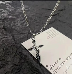Détail du collier pendentif croix argentée vintage sur fond de pierre noire texturée