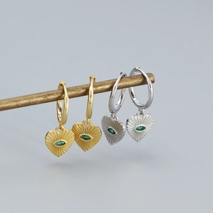 Macro detail of 925 silver heart hoop earrings in gold and silver with green zircon stones