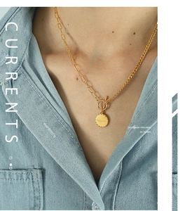 Detail of gold OT buckle necklace featuring a round pendant with Beloved engraving