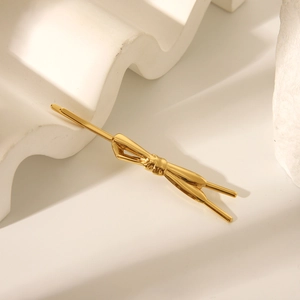 Dettaglio di un fermaglio per capelli a fiocco dorato su base geometrica bianca