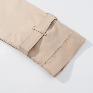 Detailed close-up of beige cropped jacket cuff with adjustable strap and stitching