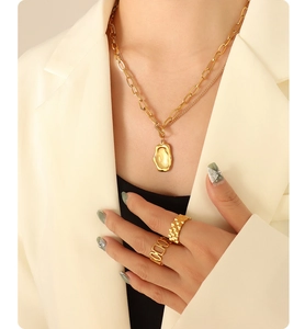 Detail of layered gold-plated titanium steel necklace with irregular pendant and rings