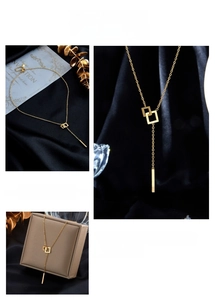 Macro shot of gold geometric square pendant with long tassel chain on luxury silk