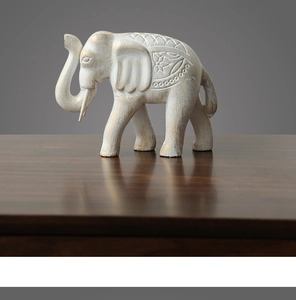 Gros plan détaillé d'une statue d'éléphant avec motifs floraux et fini blanc vieilli