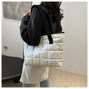 Grand sac fourre-tout matelassé argenté avec bandoulières noires porté par un modèle
